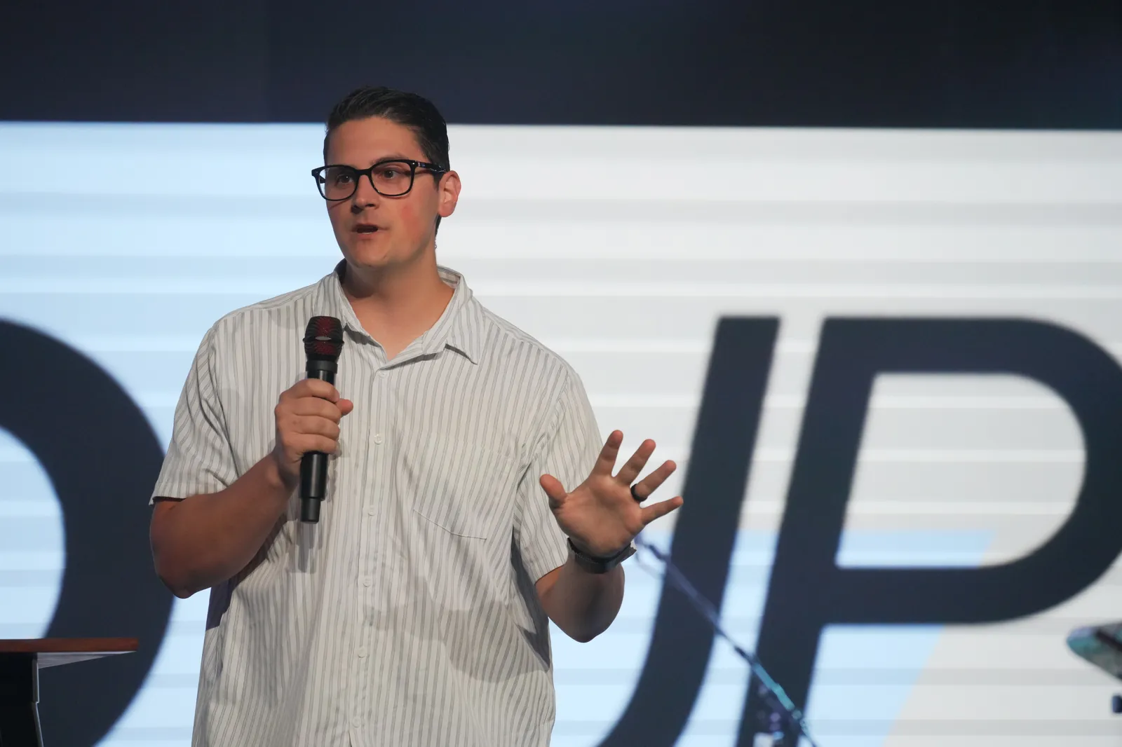 Carlo Orlando teaching from the stage at Calvary Temple International, one hand open